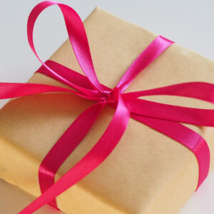 Parcel in brown paper wrapped in pink ribbon
