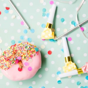 Birthday scene - donuts and party blowers on spotty tablecloth