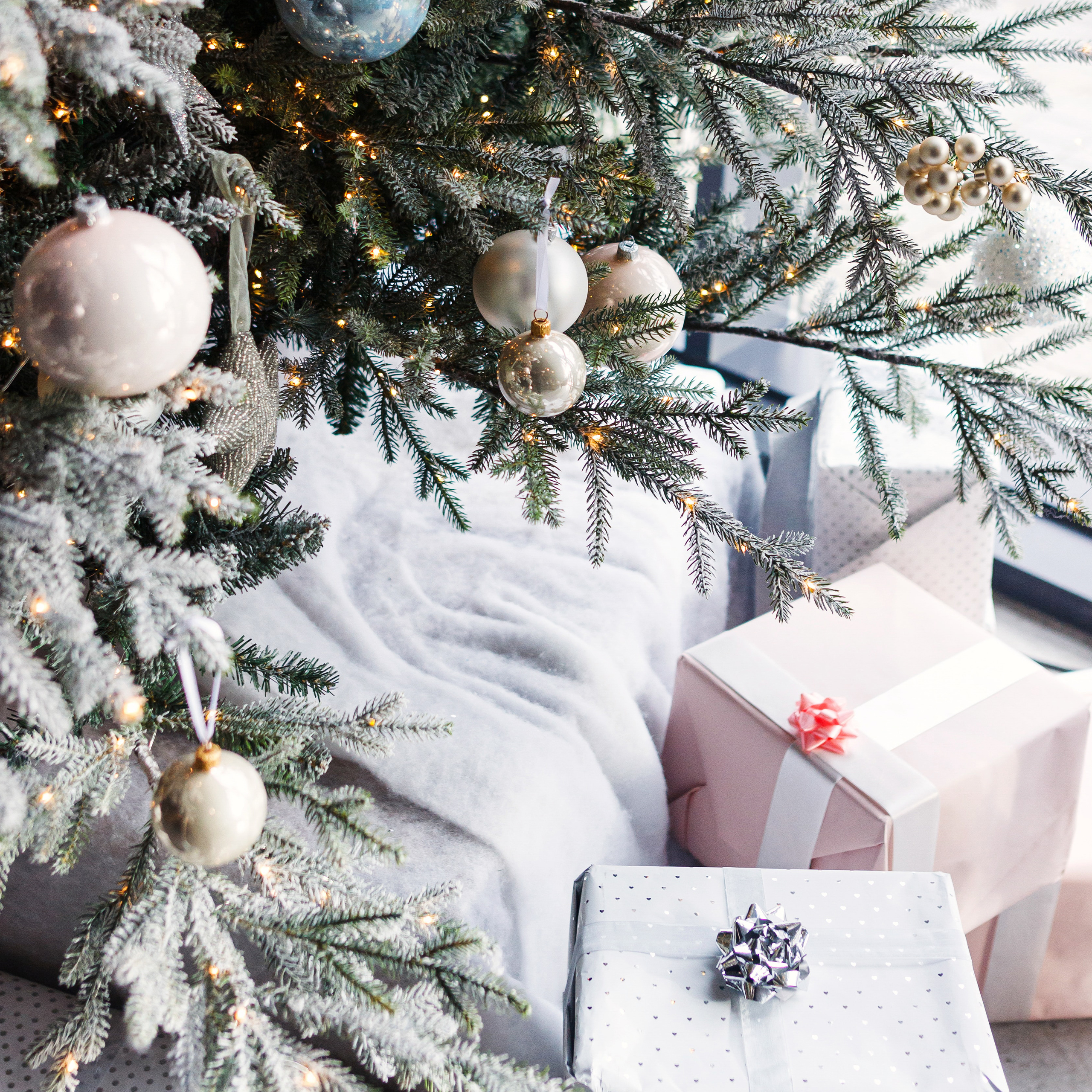Christmas presents under a tree, with a white snowy theme